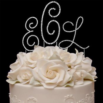 White cake with floral decorations and a decorative letter 'L' on a black background